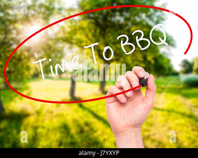Man mano che scrive il tempo di barbecue con pennarello nero su schermo visivo. Isolato sulla natura. Business, tecnologia internet concetto. Foto Stock