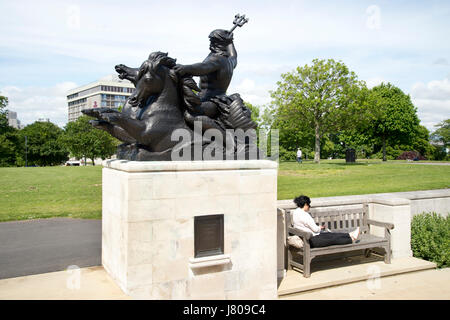 Plymouth, Devon. Nettuno (Poseidon) presso la Naval War Memorial su la zappa e una donna relax su un banco di lavoro,la lettura di un libro Foto Stock