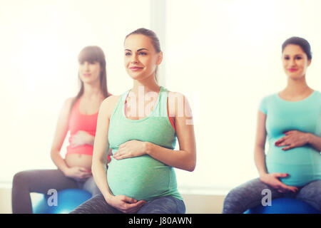 Felici le donne incinte che esercitano sulla fitball in palestra Foto Stock