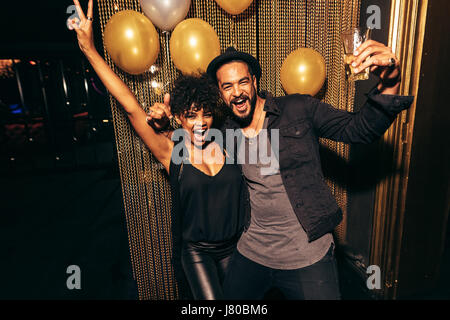 Coppia sorridente e ballare e divertirsi durante la festa in discoteca. Felice l'uomo e donna godendo di festa al nightclub. Foto Stock