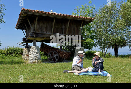 Picnic in coppia accanto a Horreo un tradizionale granaio delle Asturie arroccato su scogliere che si affacciano sull'Atlantico a Cadavedo, Asturie, Spagna. Vacanze Foto Stock