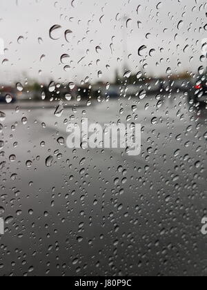 Le gocce di pioggia sul vetro con il trasporto su strada in background Foto Stock