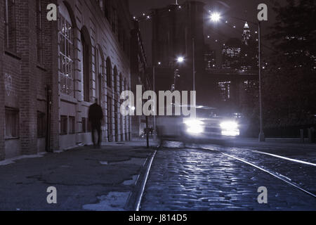 Notte vanishing point visualizza in basso Plymouth Street in DUMBO, il Ponte di Brooklyn area, lunga esposizione sfondo con look rétro. Il sodio street luci accese e Foto Stock