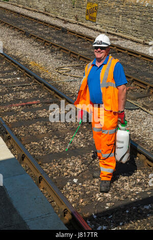 L'uomo la spruzzatura di erbacce lungo i binari ferroviari a Swanage nel Maggio Foto Stock