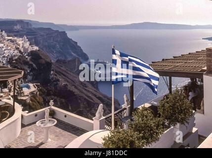 Oia - Santorini, Grecia. 29Sep, 2004. Una bandiera greca vola nel pittoresco villaggio di Oia - Santorini, arroccato sulla ripida bordo della caldera cliffs, con vedute del mare, il membro più meridionale delle Cicladi isola del gruppo e colorati di Santorini è una preferita dai turisti e la nave da crociera di destinazione. Credito: Arnold Drapkin/ZUMA filo/Alamy Live News Foto Stock