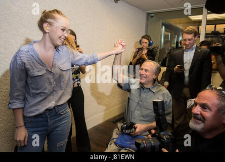 Il governatore del Texas Greg Abbott battendo il cinque di sua figlia Audrey dopo che ella gli incendi una Sig Sauer P320 9mm pistola con un silenziatore a bersagli in un nuovissimo Texas indoor gamma pistola. Abbott precedentemente firmato un disegno di legge per abbassare i costi delle licenze per i Texans. Foto Stock