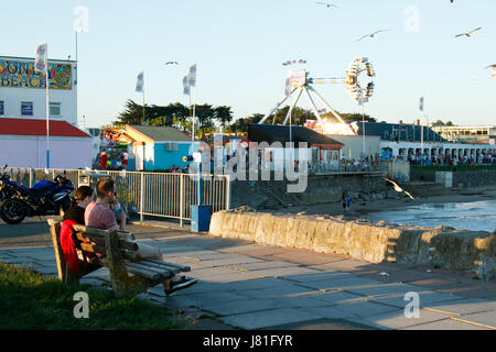 Porthcawl, South Wales, Regno Unito. 26 maggio 2017. Regno Unito: meteo persone siedono lungo la passeggiata a mare con spiaggia di Coney fair in background, come la folla godetevi il clima mite, su uno dei giorni più caldi dell'anno finora. Credito: Andrew Bartlett/Alamy Live News Foto Stock