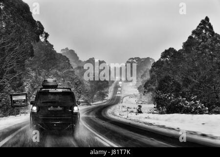Telecomando scivolosa strada di montagna nella valle di Thredbo durante la nevicata e storm fine al tramonto. Sci popolare destinazione turistica per gli australiani in Snow mo Foto Stock