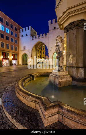 Brunnenbuberl Fontana e Karlstor cancello in serata, Monaco di Baviera, Germania Foto Stock