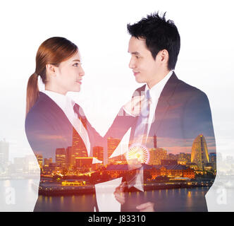 Doppia esposizione di business donna le mani al collo di regolazione tirante di uomo in tuta con una città sullo sfondo Foto Stock