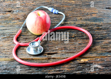 Strumenti medico uno stetoscopio dietro di Apple per una sana mettere sul tavolo di legno Foto Stock