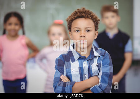Ritratto di scolaro in piedi con le braccia incrociate in aula a scuola Foto Stock