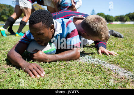 Close up uomo tenendo palla giocando a rugby nel campo Foto Stock