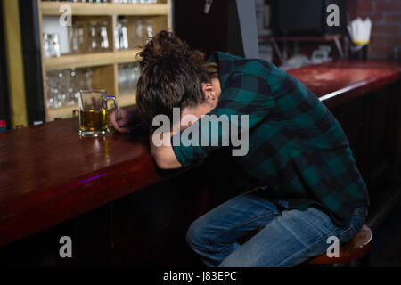 Uomo ubriaco che dorme sul bancone bar Foto Stock