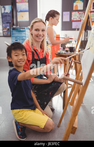 Insegnante assistere schoolboy nella classe di disegno a scuola Foto Stock