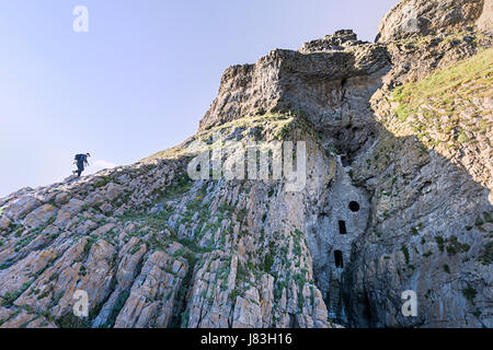 Uomo falesia di arrampicata al foro di Culver, Gower, Wales, Regno Unito Foto Stock