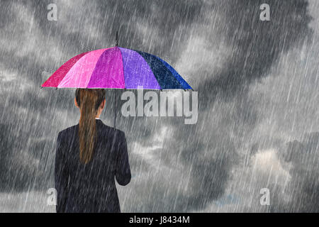 Business Woman holding ombrello multicolore sotto il cielo scuro con la caduta di pioggia Foto Stock