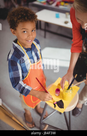 Insegnante assistere schoolboy nella classe di disegno a scuola Foto Stock