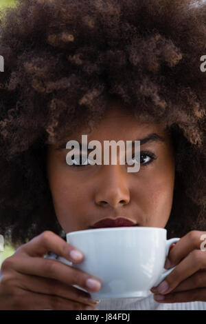 Close up ritratto di giovane donna con capelli crespi holding tazza da caffè Foto Stock