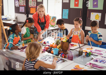 Insegnante assistere schoolkids nella classe di disegno a scuola Foto Stock