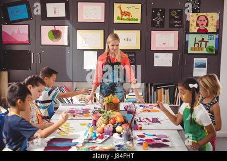 Insegnante assistere schoolkids nella classe di disegno a scuola Foto Stock