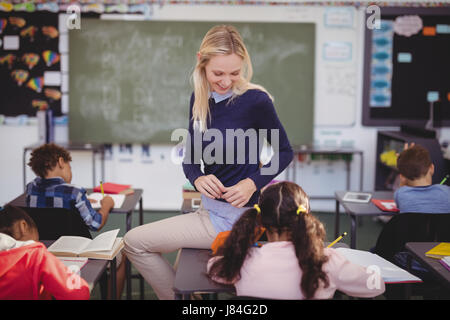 Insegnante aiutando schoolkids con i loro compiti in classe a scuola Foto Stock