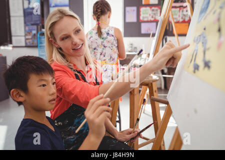 Insegnante assistere schoolboy nella classe di disegno a scuola Foto Stock