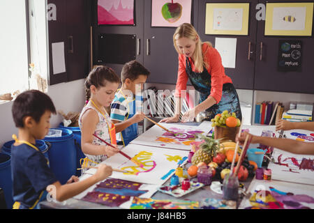 Insegnante assistere schoolkids nella classe di disegno a scuola Foto Stock