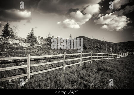 Il paesaggio con le montagne sullo sfondo e una recinzione in primo piano. Foto Stock