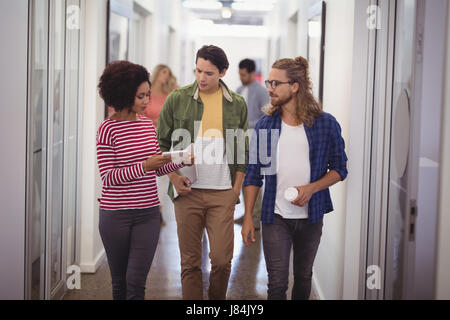 La gente di affari discutendo mentre si cammina nel corridoio in ufficio Foto Stock