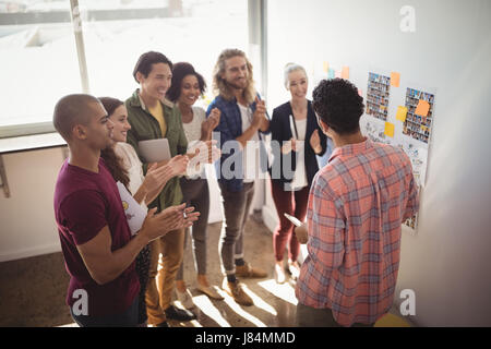 Team ad applaudire mentre imprenditore per discutere le strategie del creative office Foto Stock