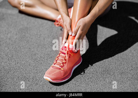 Sezione bassa di sportive che soffrono di dolore in pista durante la giornata di sole Foto Stock