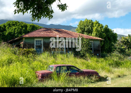 Un auto abbandonate si siede in un cantiere accanto a una proprietà abbandonati appena fuori il pi'ilani autostrada a sud di Maui, Hawaii Foto Stock