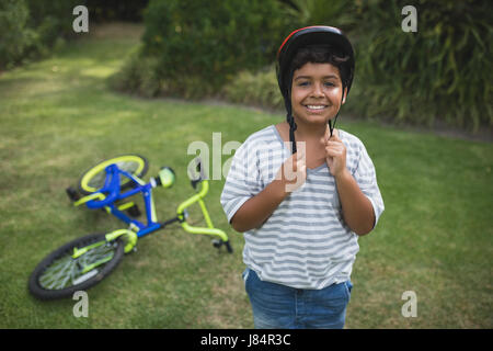 Ritratto di ragazzo sorridente indossando il casco per bicicletta rimanendo in posizione di parcheggio Foto Stock