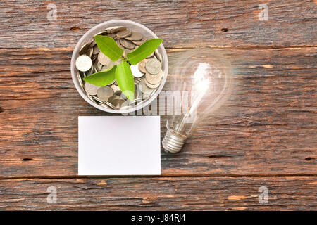 Libro bianco mock up,lampadina per idea e la pila di monete in vetro messo a portata di mano per risparmiare denaro e finanziari, imposta stagione Foto Stock