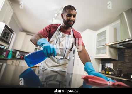 Basso angolo vista del giovane uomo pulizia bancone di marmo in cucina a casa Foto Stock