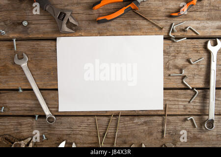 Vista aerea della carta bianca nel mezzo di utensili a mano sul tavolo di legno Foto Stock