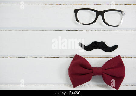 Close up of eyeglasses and bow tie with mustache arranged on white table Foto Stock
