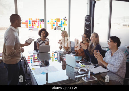 La gente di affari ad applaudire per collega dando la presentazione in ufficio Foto Stock