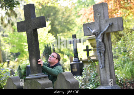 Il giardiniere Markus Preissler controlla la croce di un oggetto contrassegnato per la rimozione definitiva all'cemeterey principale di Frankfurt am Main, Germania, 9 maggio 2017. Diverse migliaia di lapidi sono controllate ogni anno per mantenere la loro integrità ed evitare incidenti. Foto: Arne Dedert/dpa Foto Stock