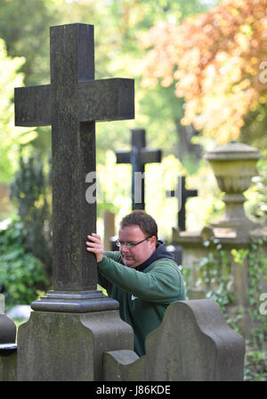 Il giardiniere Markus Preissler controlla la croce di un oggetto contrassegnato per la rimozione definitiva all'cemeterey principale di Frankfurt am Main, Germania, 9 maggio 2017. Diverse migliaia di lapidi sono controllate ogni anno per mantenere la loro integrità ed evitare incidenti. Foto: Arne Dedert/dpa Foto Stock