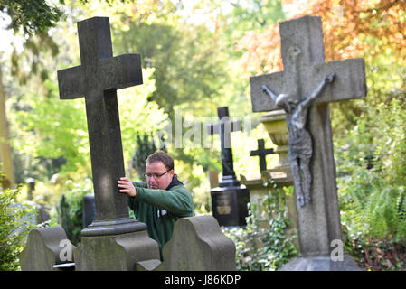 Il giardiniere Markus Preissler controlla la croce di un oggetto contrassegnato per la rimozione definitiva all'cemeterey principale di Frankfurt am Main, Germania, 9 maggio 2017. Diverse migliaia di lapidi sono controllate ogni anno per mantenere la loro integrità ed evitare incidenti. Foto: Arne Dedert/dpa Foto Stock