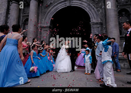 Gli ospiti gettano i confetti sopra la sposa e lo sposo durante un cinese Matrimonio nella chiesa cattolica romana di San Agustin o Iglesia De la Inmaculada Concepcion de Maria de San Agustin situato Situato all'interno della storica città murata di Manila cui si fa riferimento Come Intramuros nella città di Manila capitale del Filippine Foto Stock