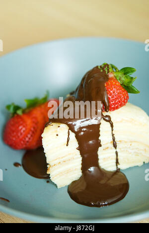 Crêpe Torta di cioccolato e fragola sul vaso blu su legno marrone chiaro tabella Foto Stock