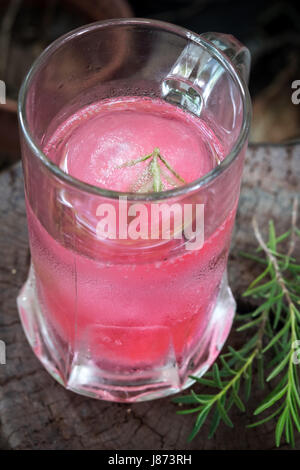 Aroma di lampone ghiaccio in acqua di soda decorate con rosmarino posto sul moncone di legno Foto Stock