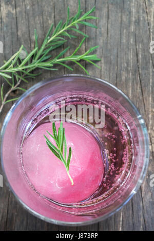 Aroma di lampone ghiaccio in acqua di soda decorate con rosmarino posto sul moncone di legno Foto Stock
