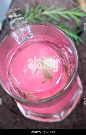Aroma di lampone ghiaccio in acqua di soda decorate con rosmarino posto sul moncone di legno Foto Stock