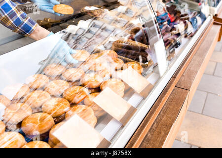 Il venditore ottiene una mano. torta fatta in casa scones display su un quadrato sotto vetro showcase street trading nel mercato, fast food Foto Stock