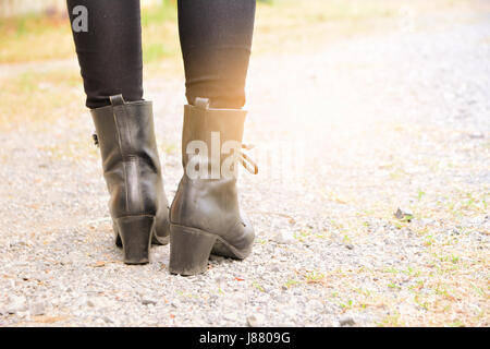 Una donna gambe indossando stivali neri con tacco alto. Foto Stock