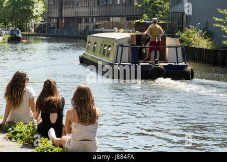 Tre giovani donne seduti su un canale banca in King's Cross, London, Regno Unito Foto Stock